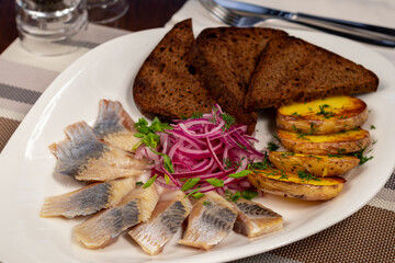 Poster - Herring with potatoes, red onion and black bread on white plate