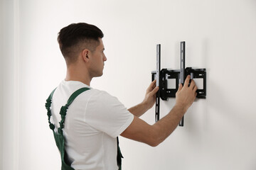 Canvas Print - Professional technician installing TV bracket on wall indoors