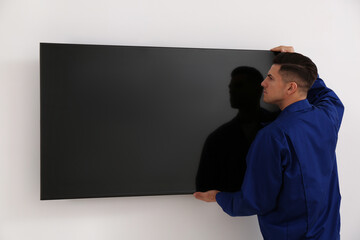 Wall Mural - Professional technician installing modern flat screen TV on wall indoors