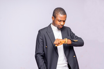 Portrait of a shocked and worried black businessman looking at his wrist watch, an African American male in a suit who is afraid of being late for a meeting isolated over a white studio background