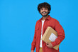 © insta_photos - Happy indian young man customer or courier holding parcel box isolated on blue background. Smiling guy receiving product retail order purchase in postal shipping delivery unpacking package.