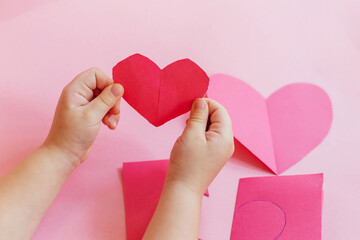 Step by step instructions. How to make a paper heart card for Valentine's Day. Creative crafts. Do it yourself. little girl cuts a heart out of paper, makes a card with her own hands 