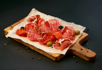 Wall Mural - Spanish cold meat assortment. Chorizo, fuet, LOMO, jamon Iberico, olives. Black background. Top view.