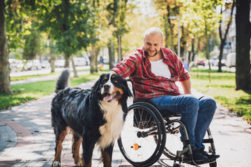 Wall Mural - Happy young man with a physical disability who uses wheelchair with his dog.