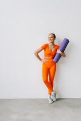 Wall Mural - Sporty woman holding yoga mat before or after fitness class on white background