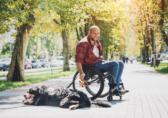 Wall Mural - Happy young man with a physical disability who uses wheelchair with his dog.