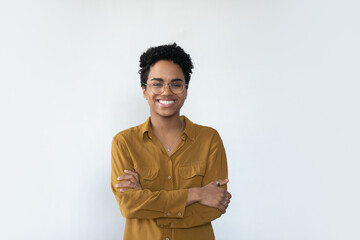 Wall Mural - Cheerful confident African businesswoman wearing eyeglasses, posing with folded arms, looking at camera with toothy smile. Millennial female customer, young woman headshot portrait isolated on white