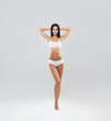 © Acronym - Attractive and slender brunette girl in white underwear posing in studio. Healthy lifestyle, sport and body care concept.