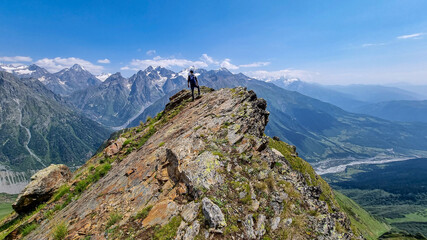 A male hiker enjoying the amazing views on the mountain ridges in the Greater Caucasus Mountain Range in Georgia, Samegrelo-Upper Svaneti Region. Freedom. Wanderlust. Trekking to Koruldi Lakes