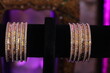 set of diamond-studded gold bangles hanging on a stand