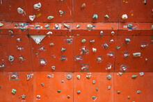 Rock Climbing Board Made Of Wood With Many Stones Plastered And Painted Red.