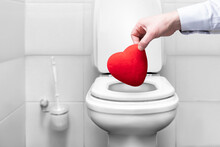 The Hand That Throws The Heart Into The Toilet Trash. A Symbol Of Broken Love And Separation. Quarrel And Breakup Of A Love Relationship Of A Love Couple Sad Valentine