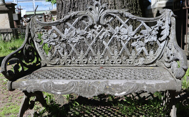 Vintage bench in cemetery, Russia. Old park metal furniture with ornaments.