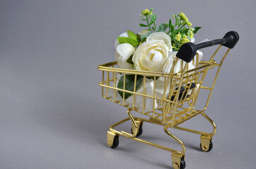 White roses in a grocery cart. Gray background.