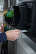 © Tof - Photographie - vue sur la main d'un homme qui met de l'essence ou du gazole dans le réservoir de sa voiture et qui paye avec sa carte de crédit