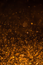 Gold Sequins Fall On A Black Background. Holiday, Shine. Texture With Bokeh