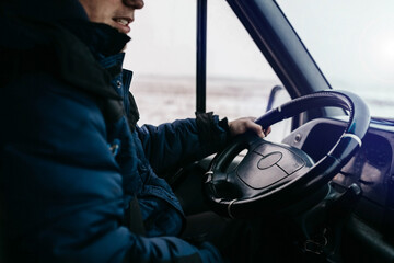 trucker driver sits behind the wheel in winter clothes in winter.