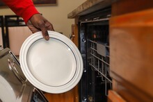 A African-American Man Putting A Dish In A Dishwasher
