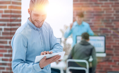 Canvas Print - Handsome businessman using a tablet in the office.