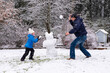 They play snowballs. A middle-aged man and a 5-year-old child make a snowman. Fun and happiness with family.