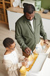 © Seventyfour - Vertical high angle portrait of African-American father and son sorting household waste at home