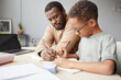 © Seventyfour - Side view portrait of African-American boy studying at home with father helping, homeschooling concept