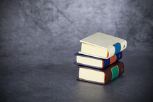 Three Thick Books In Pile On Gray Background