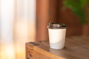 Wall Mural - Closeup of disposable take away paper cup of hot coffee on wooden table.