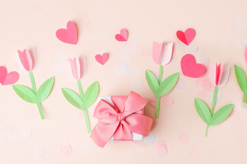 Wall Mural - Gift present box with pink bow decorated paper hearts and tulip flowers on pink pastel table top view. Flat lay composition for birthday, valentine, mother day, 8 march, wedding, paper art decor