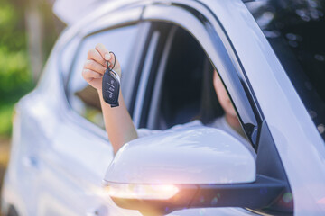 Young asian woman taking car key, keyless stystem for start car engine. Selected focus