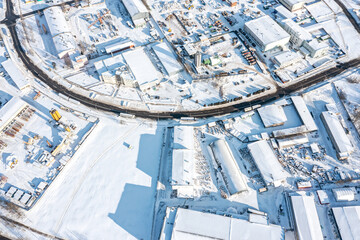 Wall Mural - aerial view of the urban industrial district with snow-covered buildings and machinery