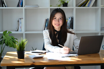 Wall Mural - Charming asian businesswoman working with computer laptop and smiling at camera.