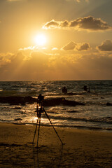 People are playing in the sea against a red sunset with clouds . Gold sea. High quality photo