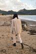 © Дарья Чачева - Elegant woman walking. Sand beach. Sea view. Beautiful sunset. Summer landscape. Without face. Soft light and natural colors. Brunette, beige suit. Meditation.