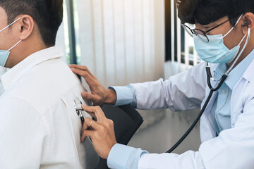 Wall Mural - Asian doctor is using a stethoscope listen to the heartbeat of the patient.