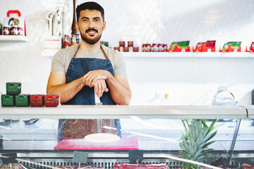 Wall Mural - Portrait of confident young salesman standing in butcher's shop