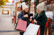 © Westend61 - Cheerful friends with shopping bags toasting wine mugs at Christmas Market
