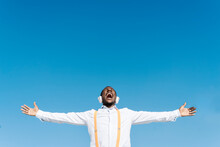 Carefree Man Screaming With Arms Outstretched In Front Of Blue Sky