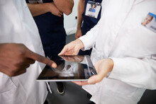 Healthcare Workers Discussing On Tablet PC At Hospital