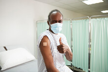 Patient With Vaccinated Arm Showing Thumbs Up Gesture In Medical Room
