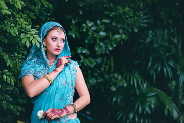 Beautiful young indian woman in traditional clothing with bridal makeup and jewelry. gorgeous bride traditionally dressed Outdoors in India. Girl bollywood dancer in Sari and henna on hands