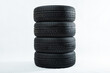 Stack of winter tires with specific structure and deep ridges shot in studio. Black rubbers for car piled on top of each other isolated on white background. Four driving wheels with copy space.