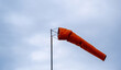 © Rawf8 - Windsock blow on cloudy sky. Red cone for wind speed and direction at the airport