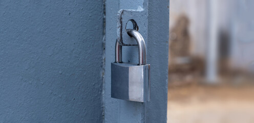 Heavy metal padlock on an open entrance gate, closeup view