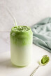Glass of dalgona matcha latte and spoon of green tea powder.