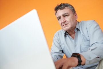 Wall Mural - Senior businessman working on laptop, coding or checking e-mails from colleagues