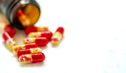 red capsule of medicine and bottle on white background