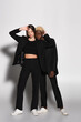 © LIGHTFIELD STUDIOS - african american with bleached hair looking at camera near stylish woman on grey with shadow.