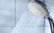 Shower Head And Water Stream In Blue Bathroom