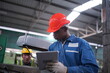© FotoArtist - Portrait of Professional Heavy Industry Engineer / Worker Wearing Safety Uniform, Goggles and Hard Hat. In the Background Unfocused Large Industrial Factory